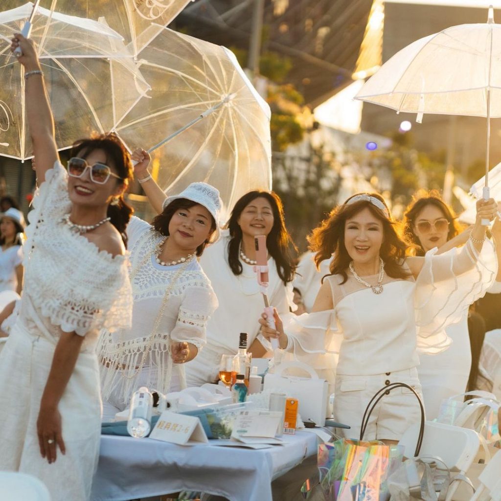 無數全白身影,在落日餘暉、消逝黑夜間,舉杯共享
傘和傘之間一點一點光亮此起彼落,…